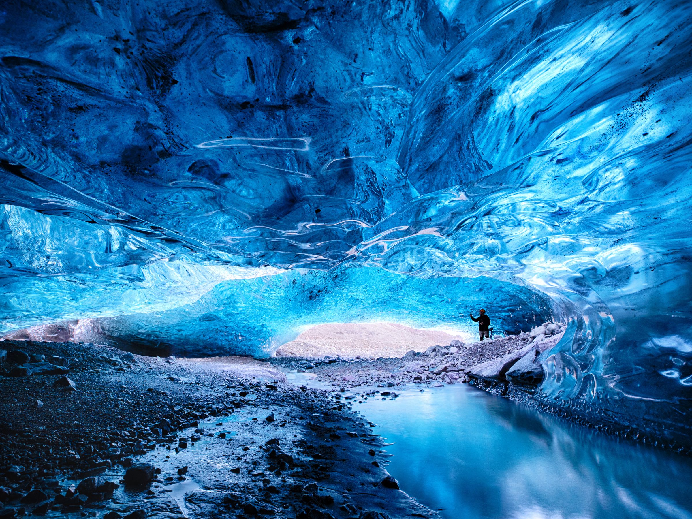 a person is standing inside of a blue ice cave at skaftafell in south iceland.
