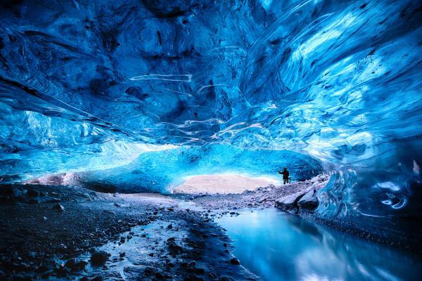 a person is standing inside of a blue ice cave in iceland.