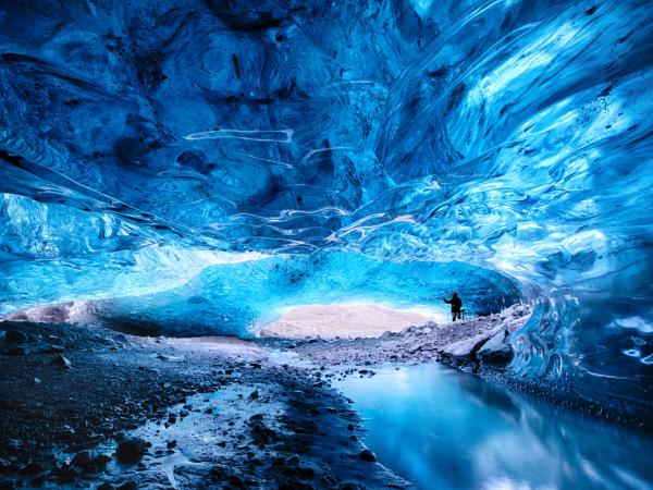 a person is standing inside of a blue ice cave at skaftafell in south iceland.