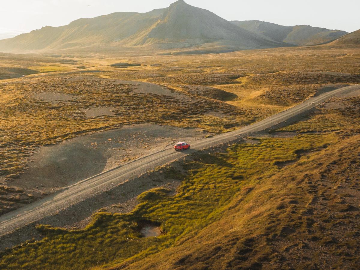 Vitara vue aérienne sur route ouverte Petite Suzuki Vitara rouge sur une route de gravier traversant un paysage montagneux dégagé