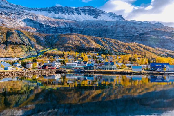 a small town on the shore of a lake with mountains in the background .