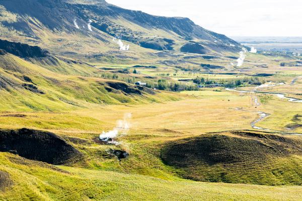 a valley with a mountain in the background and a river running through it, Reykjadalur
