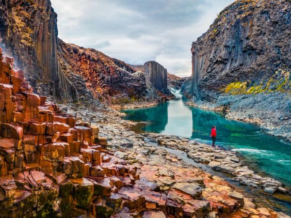 Chico vestido de rojo en la orilla del río del cañón Studlagil