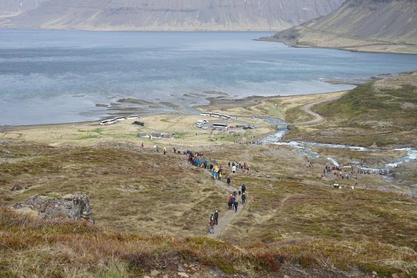 a group of people are walking down a path next to a lake .