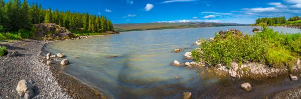 una vista panorámica de un lago rodeado de árboles en un día soleado.