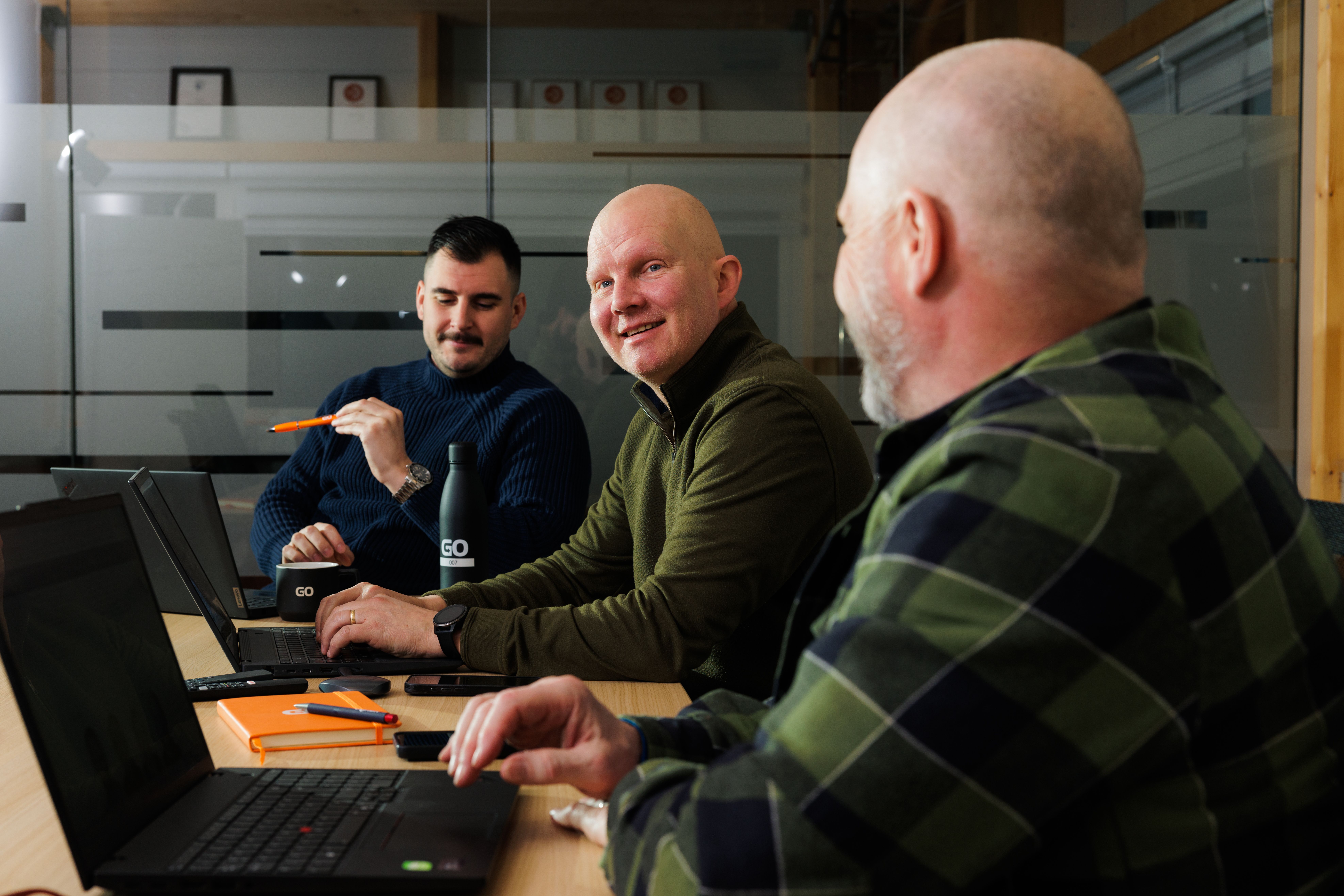 un groupe d’hommes assis à une table avec des ordinateurs portables.