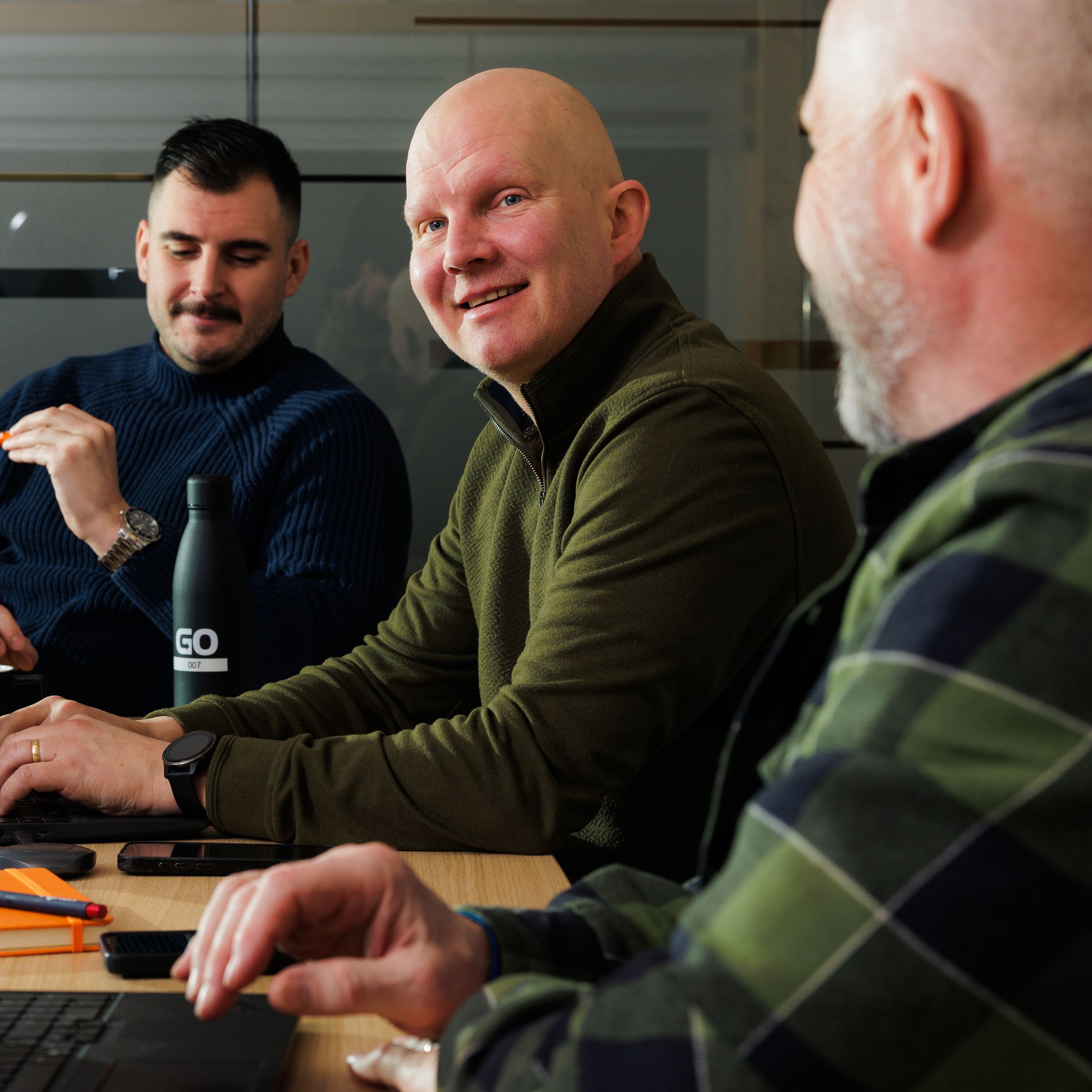 un groupe d’hommes assis à une table avec des ordinateurs portables.