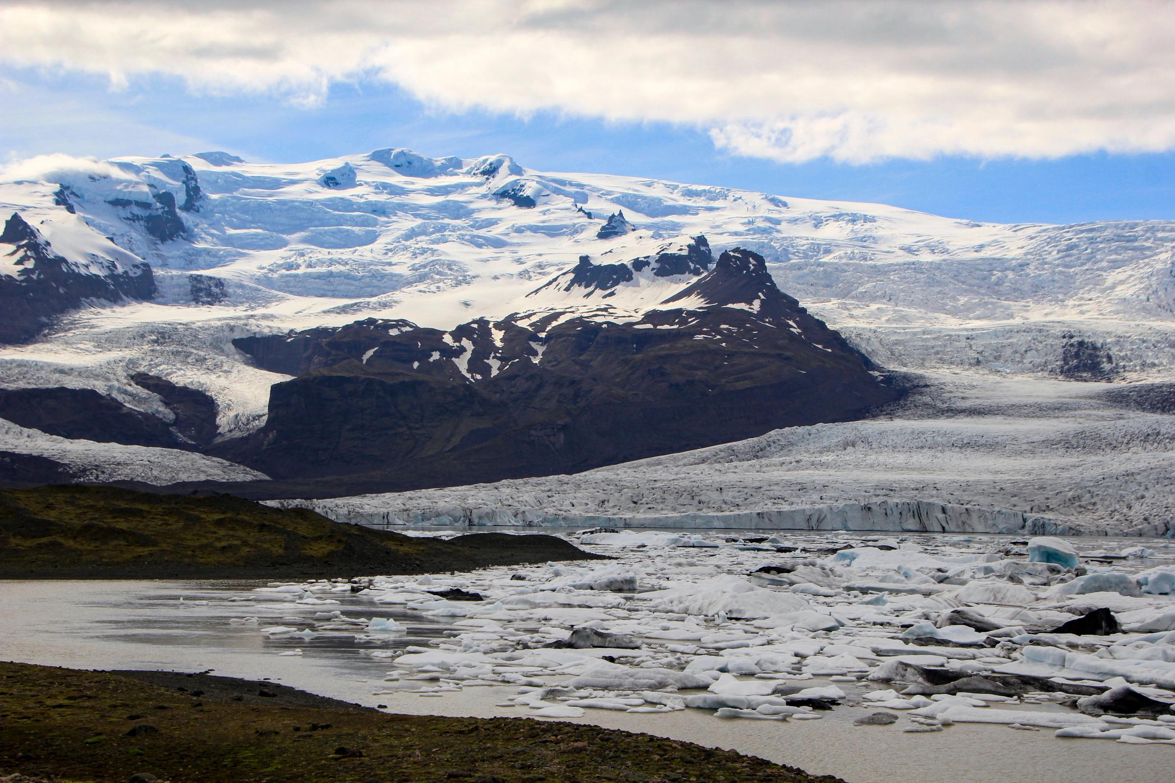 a large body of water surrounded by snow covered mountains .