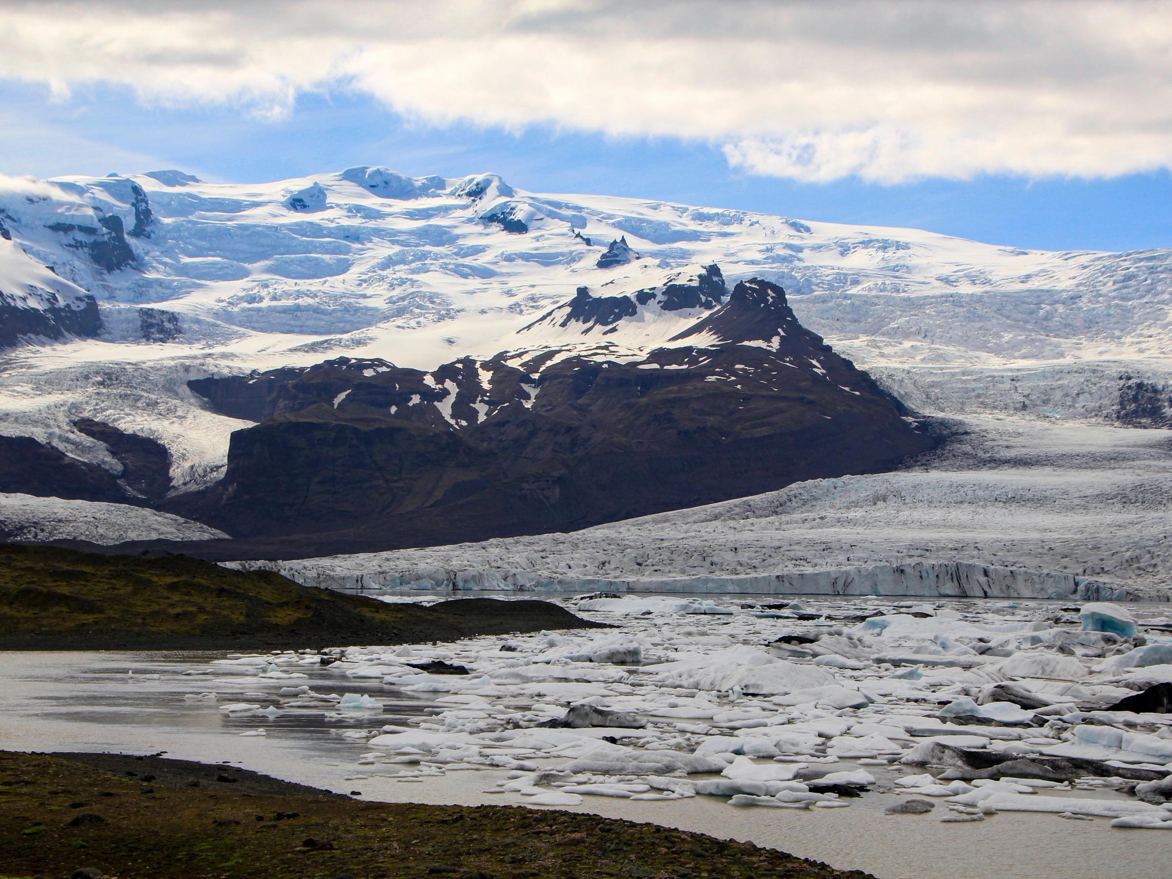 a large body of water surrounded by snow covered mountains .
