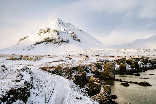 an aerial view of a snowy landscape with a mountain in the background at Arnarstapi in iceland.