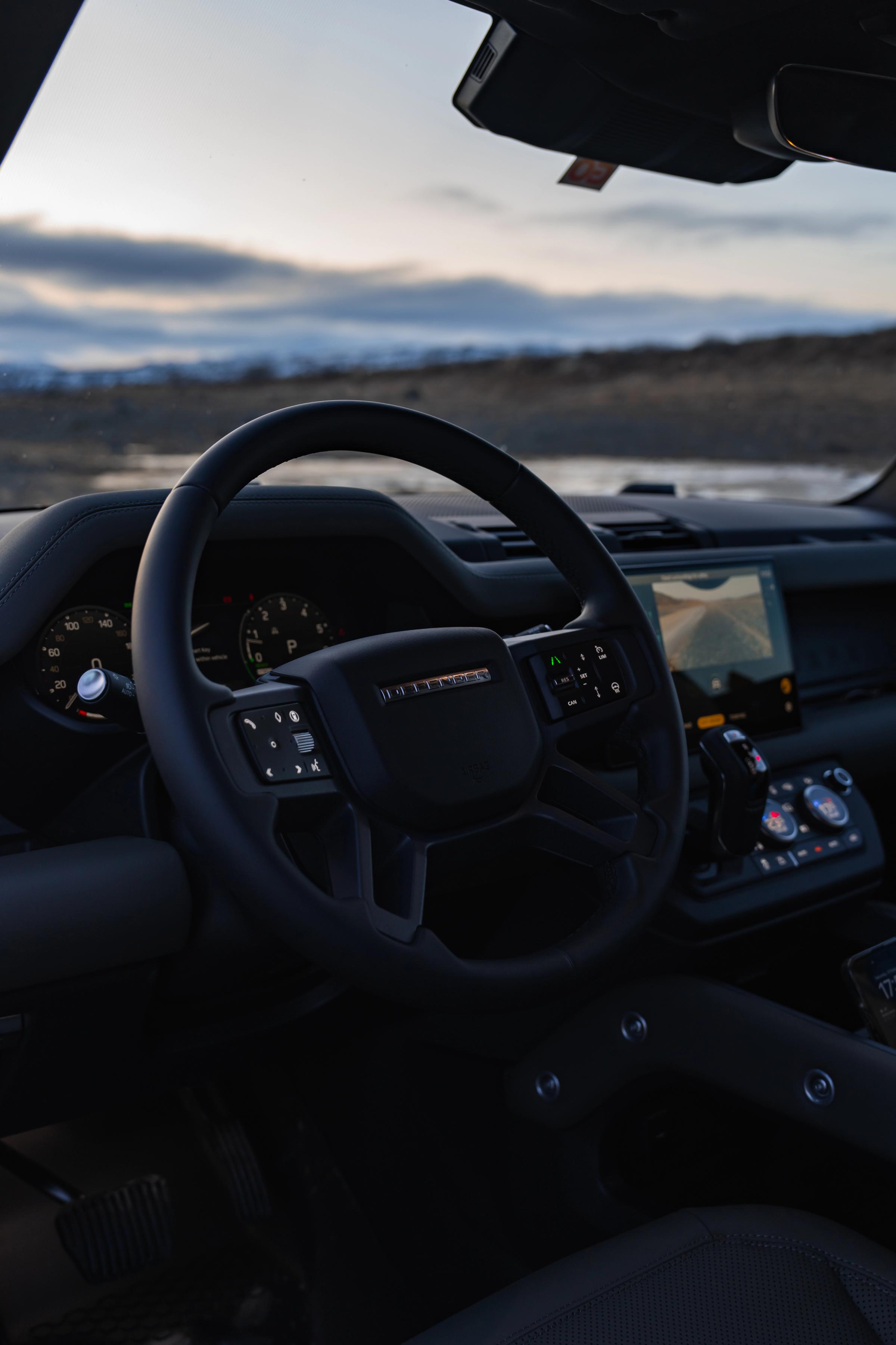 Interior de un Land Rover Defender en el que se ven el volante, el cuadro de instrumentos y la pantalla táctil