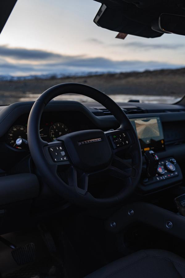 Interior de un Land Rover Defender en el que se ven el volante, el cuadro de instrumentos y la pantalla táctil