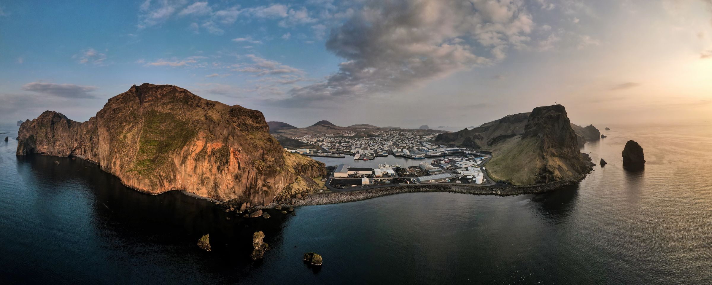 an aerial view of a small island in the middle of the ocean at sunset at Westman Islands in iceland.
