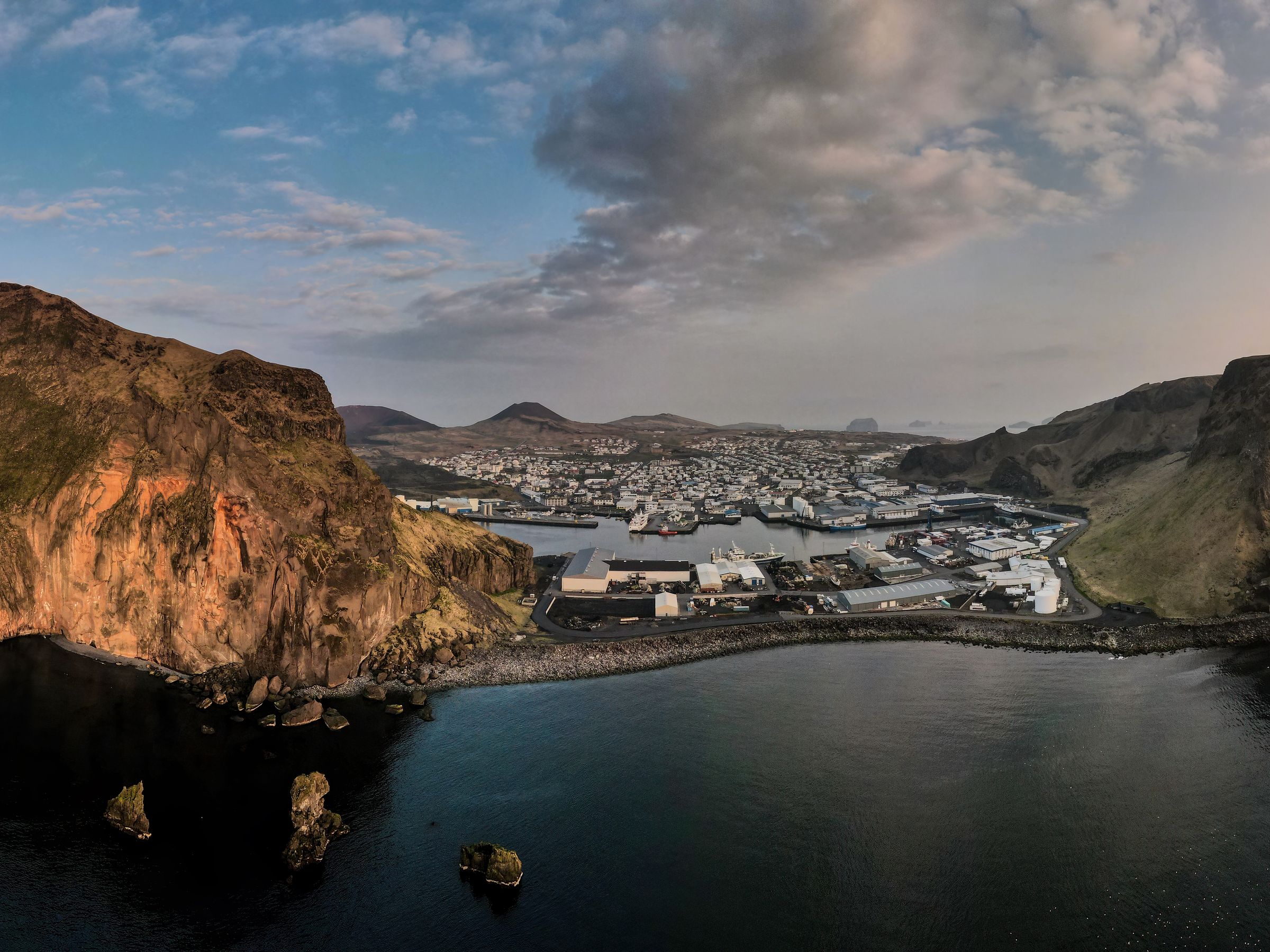 an aerial view of a small island in the middle of the ocean at sunset at Westman Islands in iceland.