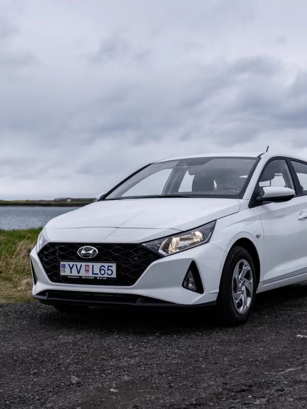 Hyundai i20 blanco aparcado en una carretera con un lago detrás