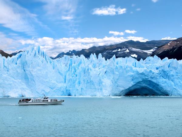 a boat is floating in the water in front of a large iceberg .