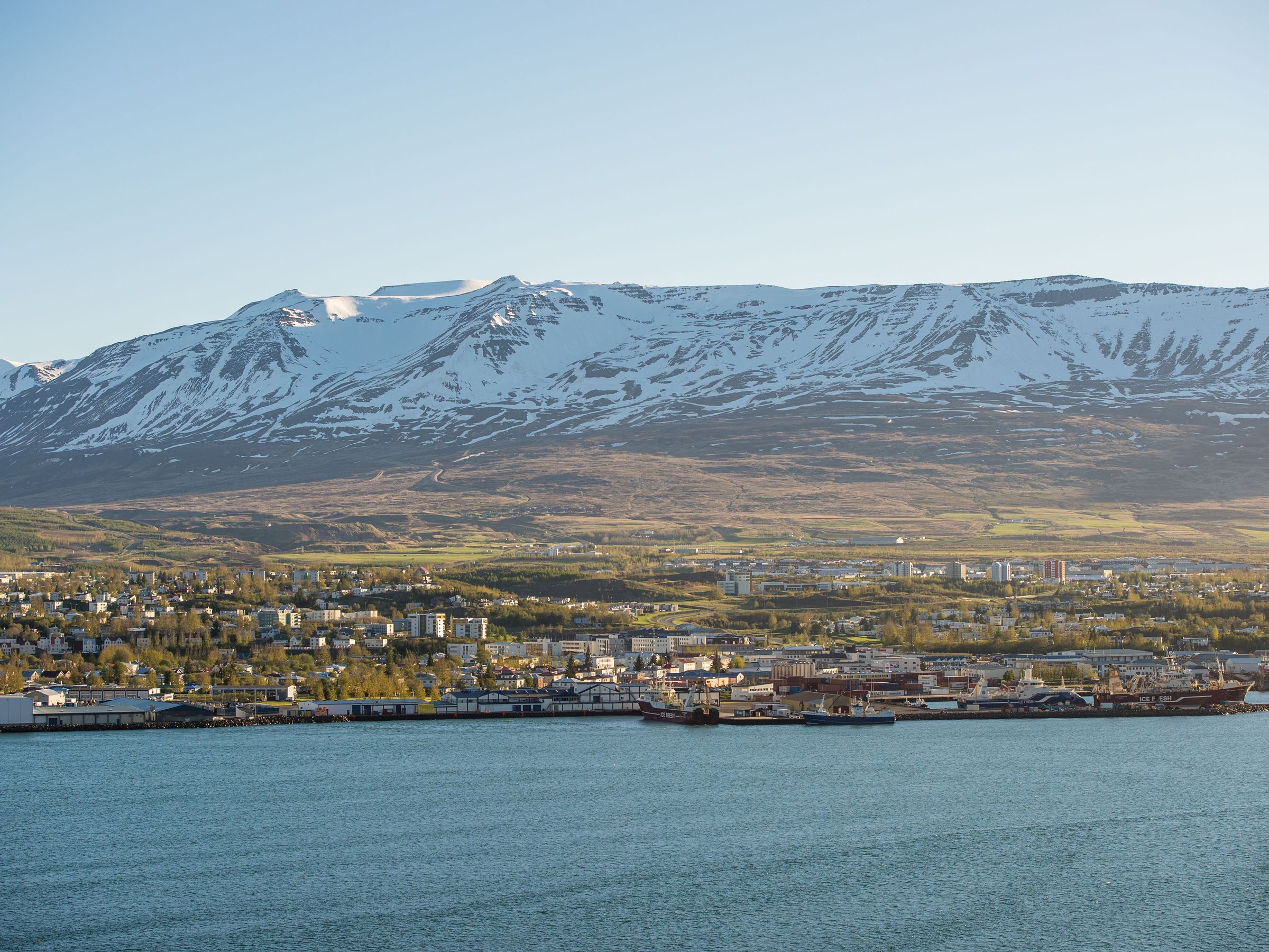 Panoramic view of a city near the sea with snow-covered mountains in the background