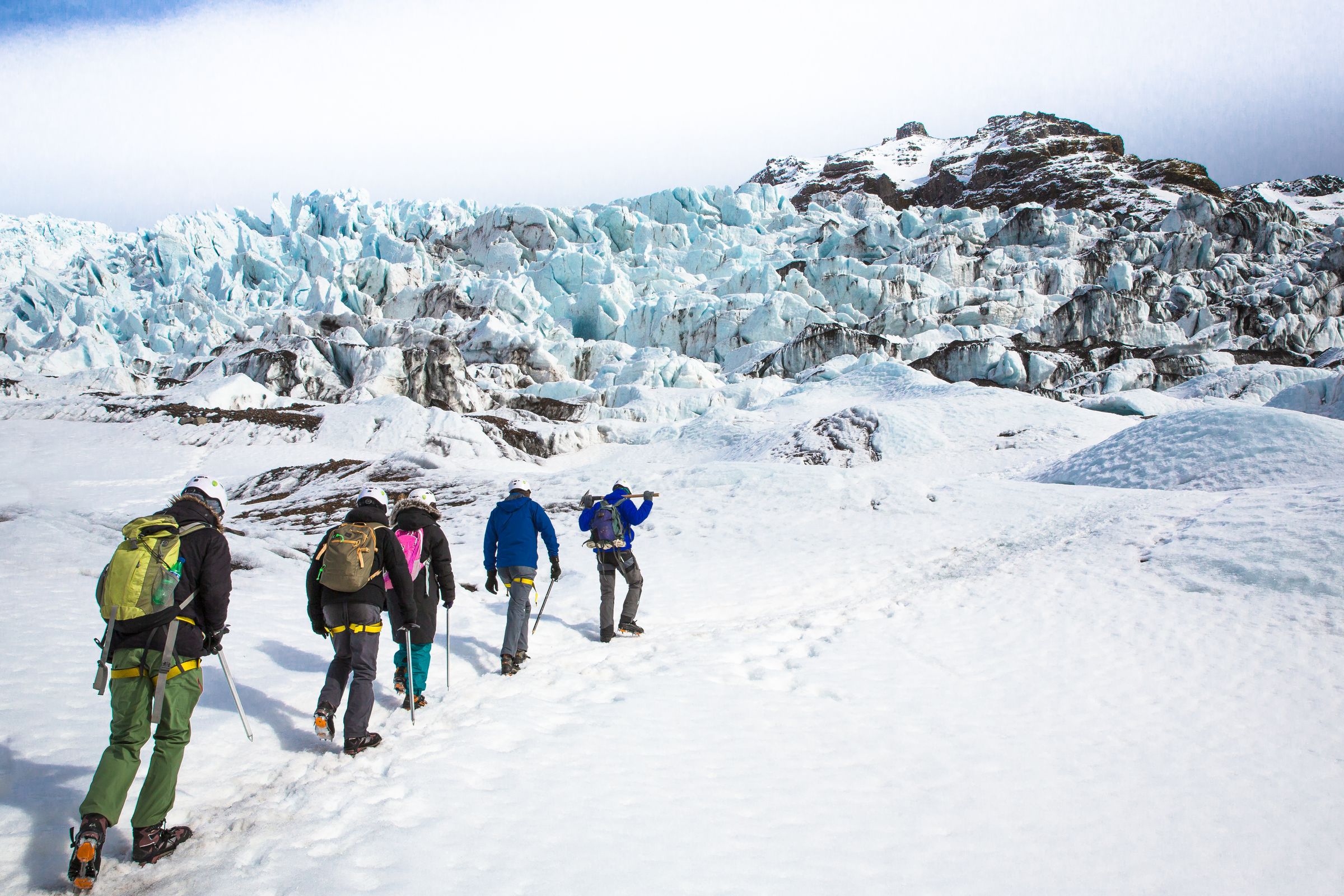 a group of people are walking in the snow near a glacier, Iceland