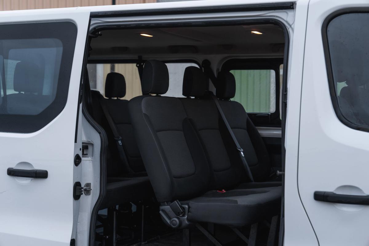 Vista del interior de una miniván Renault Trafic, con los asientos traseros de pasajeros vistos a través de la puerta lateral abierta