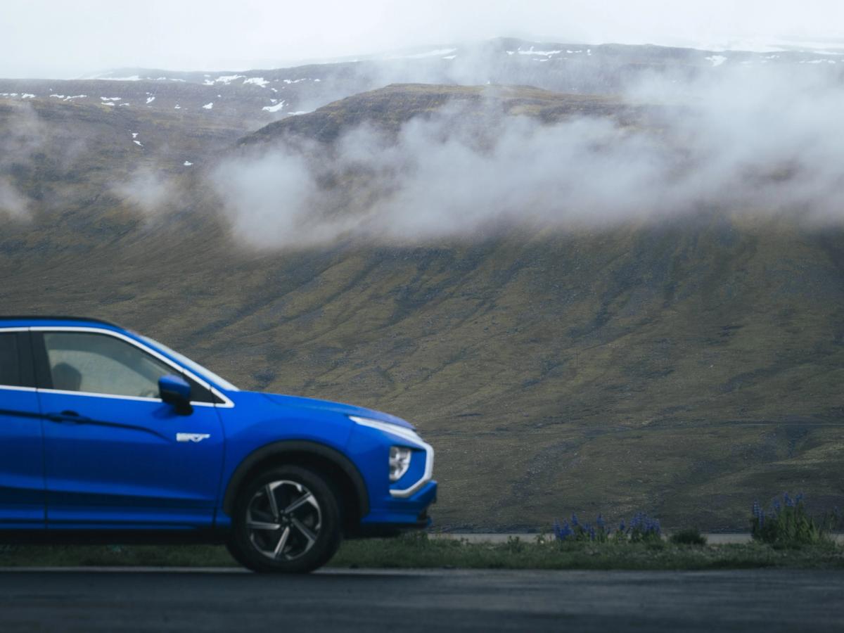 Mitsubishi Eclipse Cross Montaña de Nubes Vista lateral de un Mitsubishi Eclipse Cross aparcado, con nubes bajas descendiendo por la ladera de una montaña