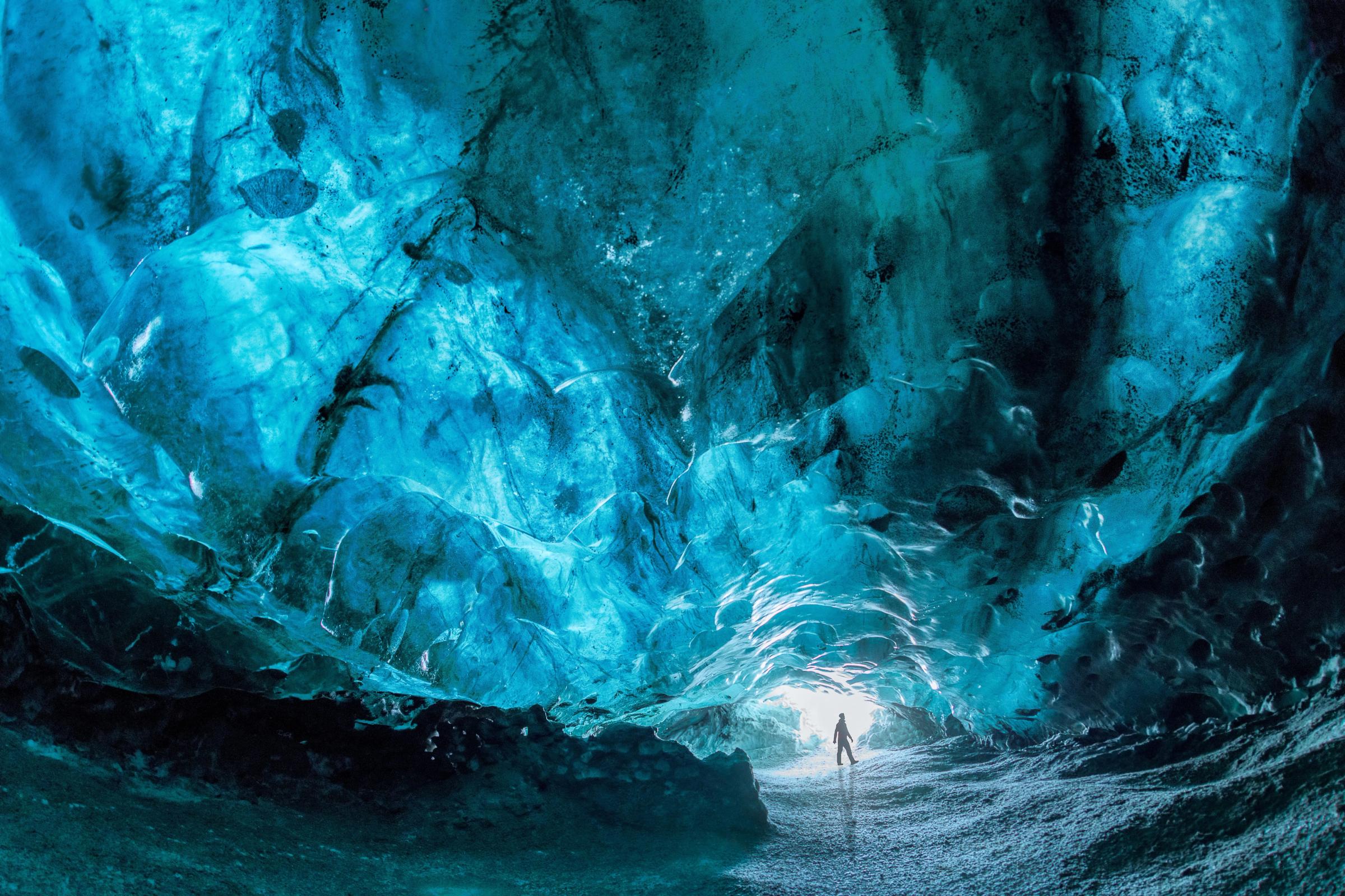 a man standing inside a blue ice cave