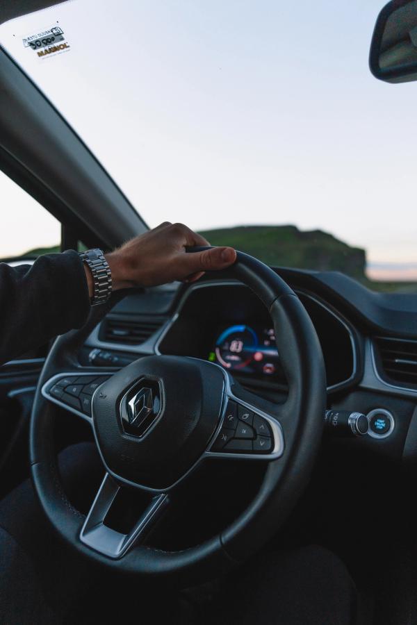 Mano en el volante del Renault Captur Volante de un Renault Captur con la mano del conductor apoyada y una colina costera visible en el exterior