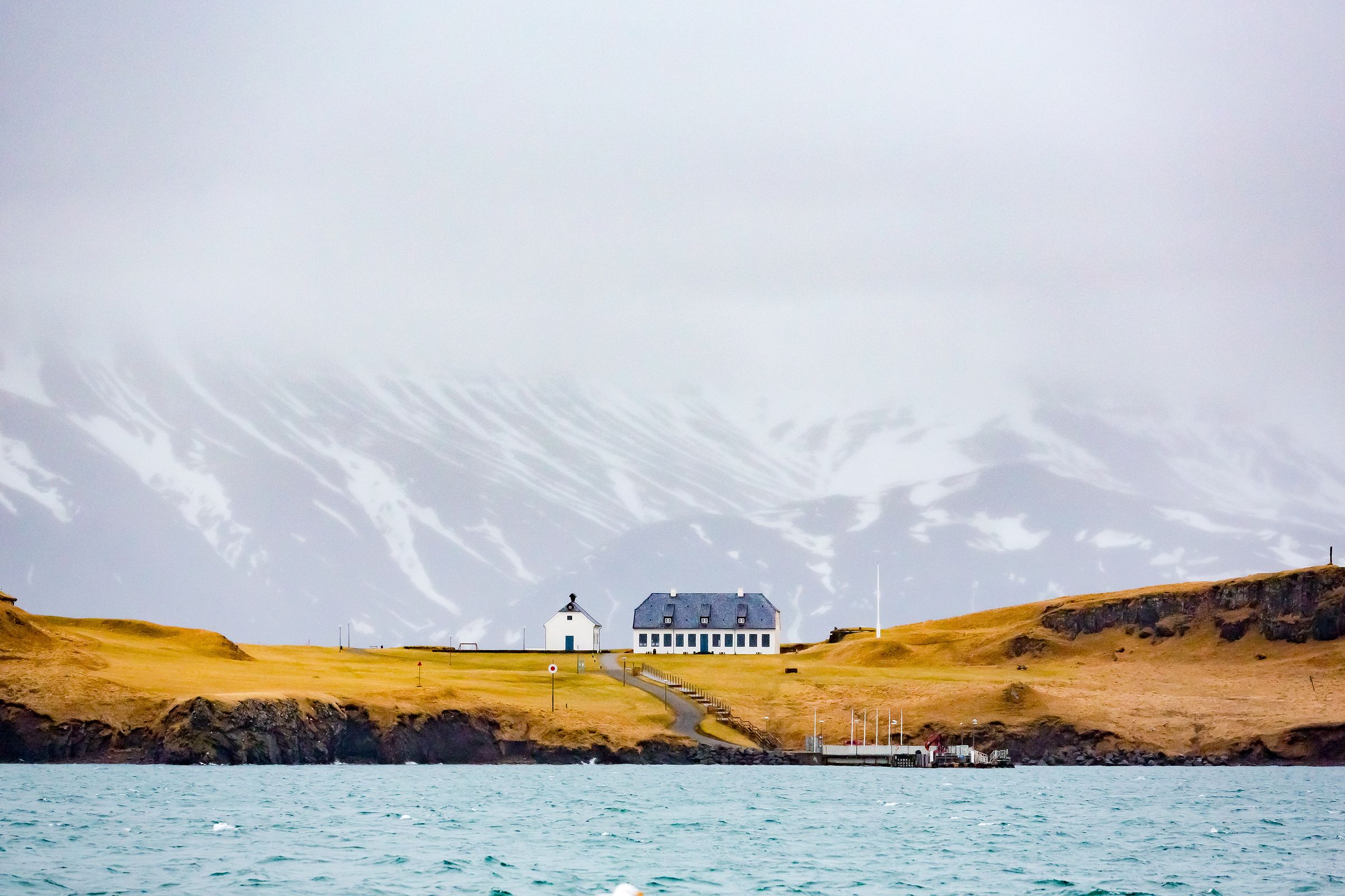 a small house is sitting on top of a hill next to the ocean .