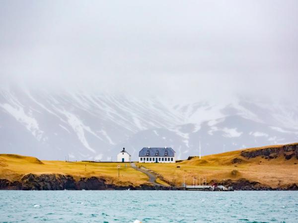 a small house is sitting on top of a hill next to the ocean .