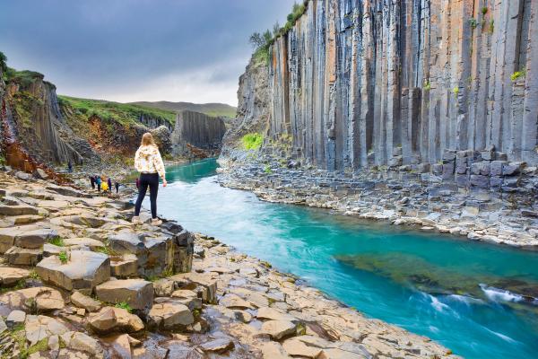 a woman is standing on a rocky cliff overlooking a river .