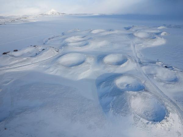 una vista aérea de un paisaje nevado con una montaña al fondo.