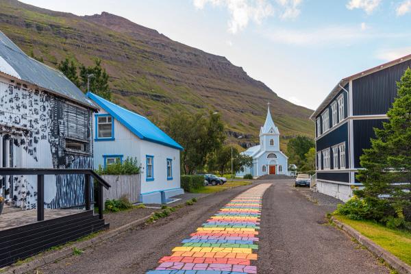 Rainbow Road in Seydisfjordur Iceland The vibrant Rainbow Road in Seydisfjordur, Iceland, stretching towards a quaint town set against mountainous scenery.