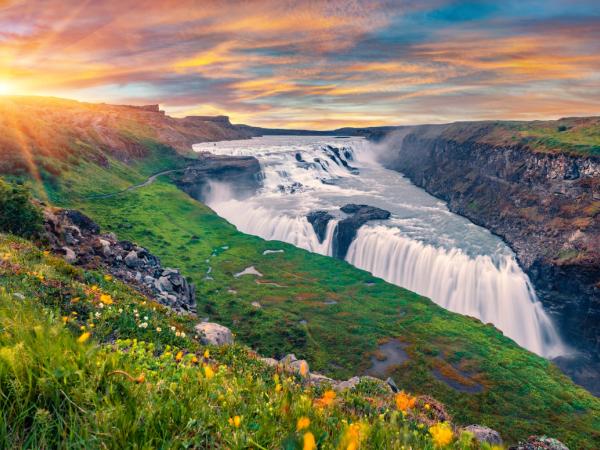 Cascada grande rodeada de un campo verde al amanecer