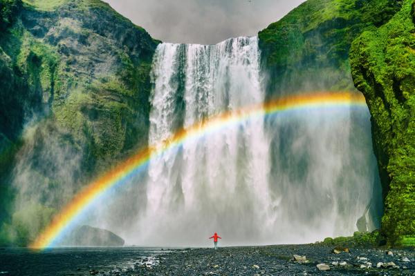 Chica en frente de Skógafoss con un arcoiris perfecto