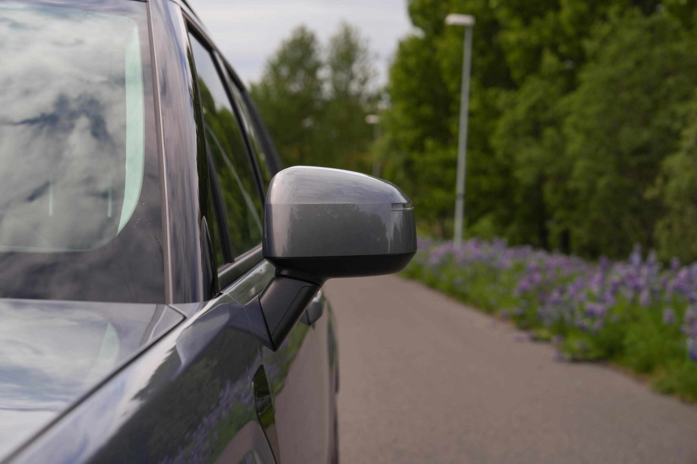 Hyundai Santa Fe wing mirror close up with a paved road and lupins in the background