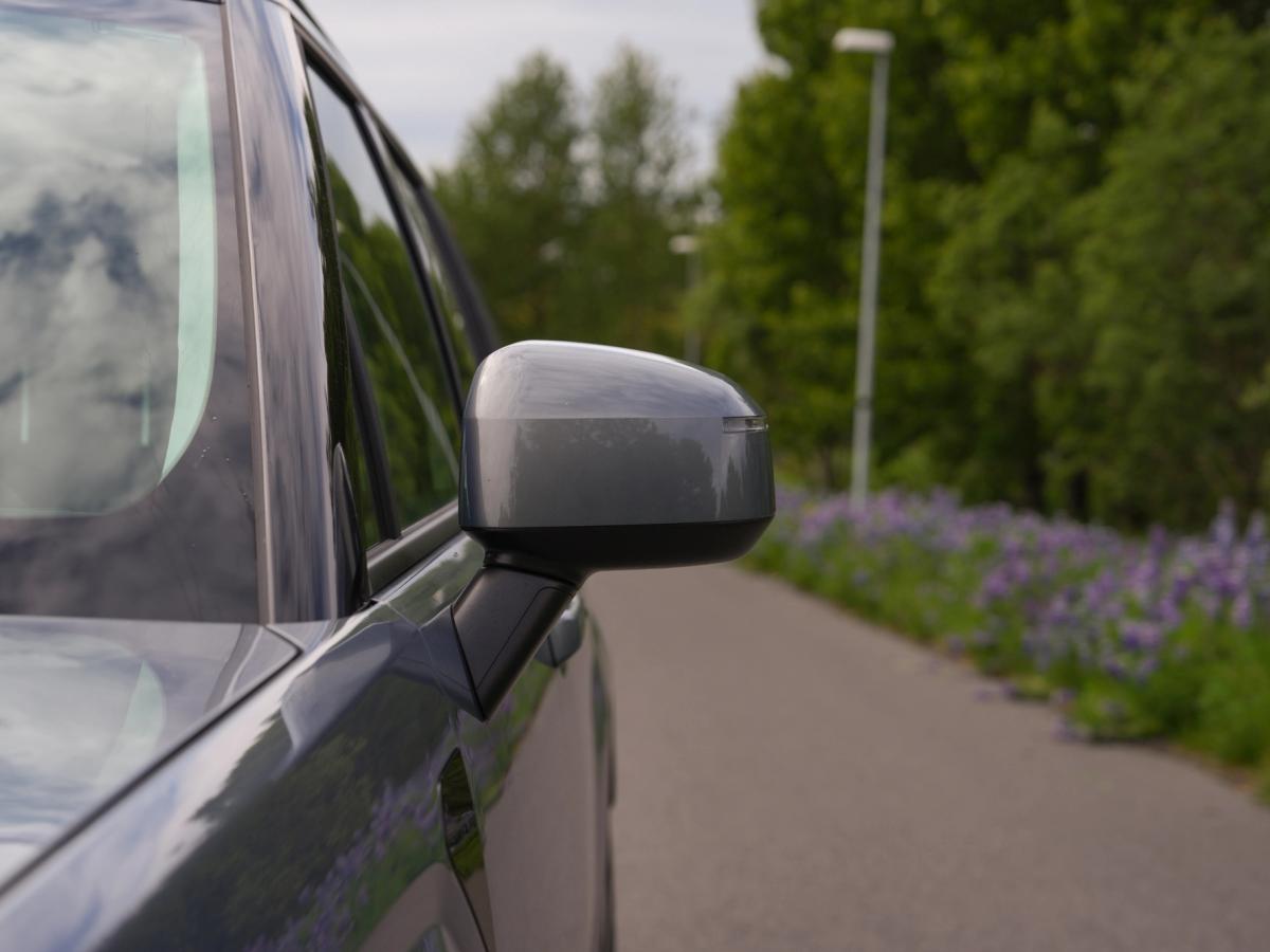 Hliðarspegill fyrir Santa Fe Nærmynd af hliðarspegli á Hyundai Santa Fe, með malbikaðan veg og lúpínur í bakgrunni