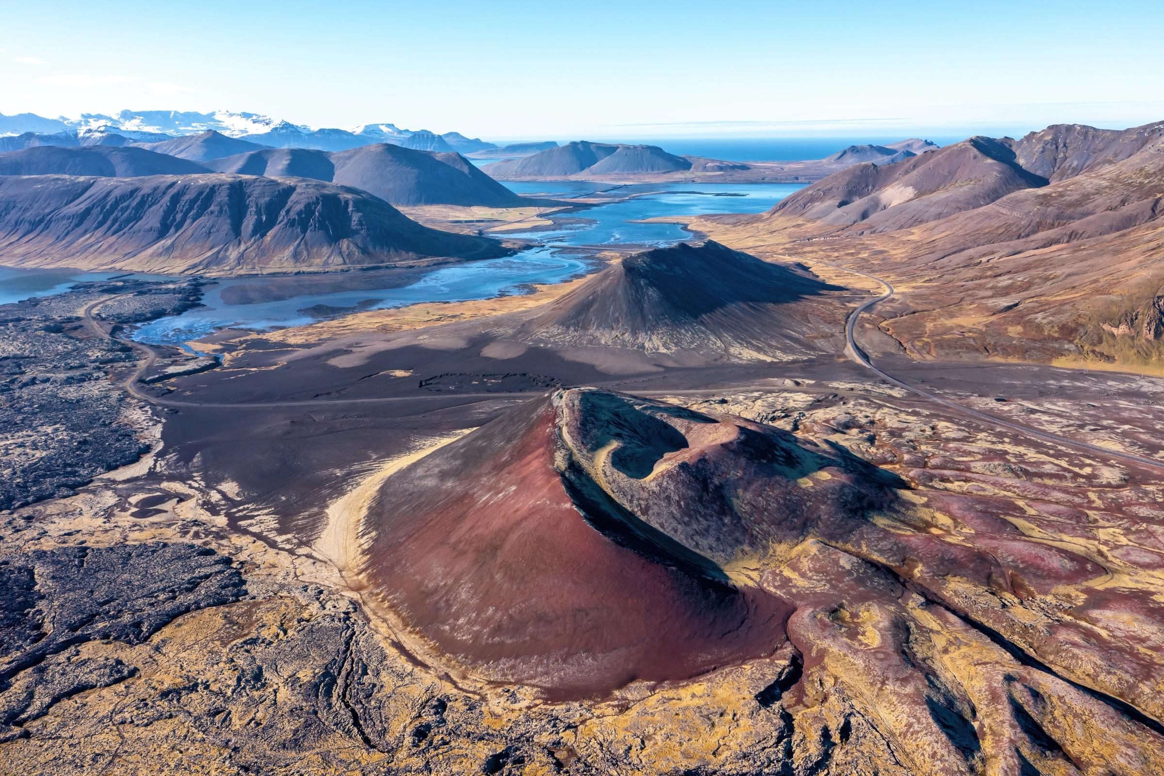 an aerial view of a volcano with mountains in the background .