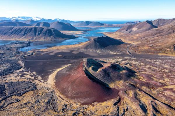 an aerial view of a volcano with mountains in the background .