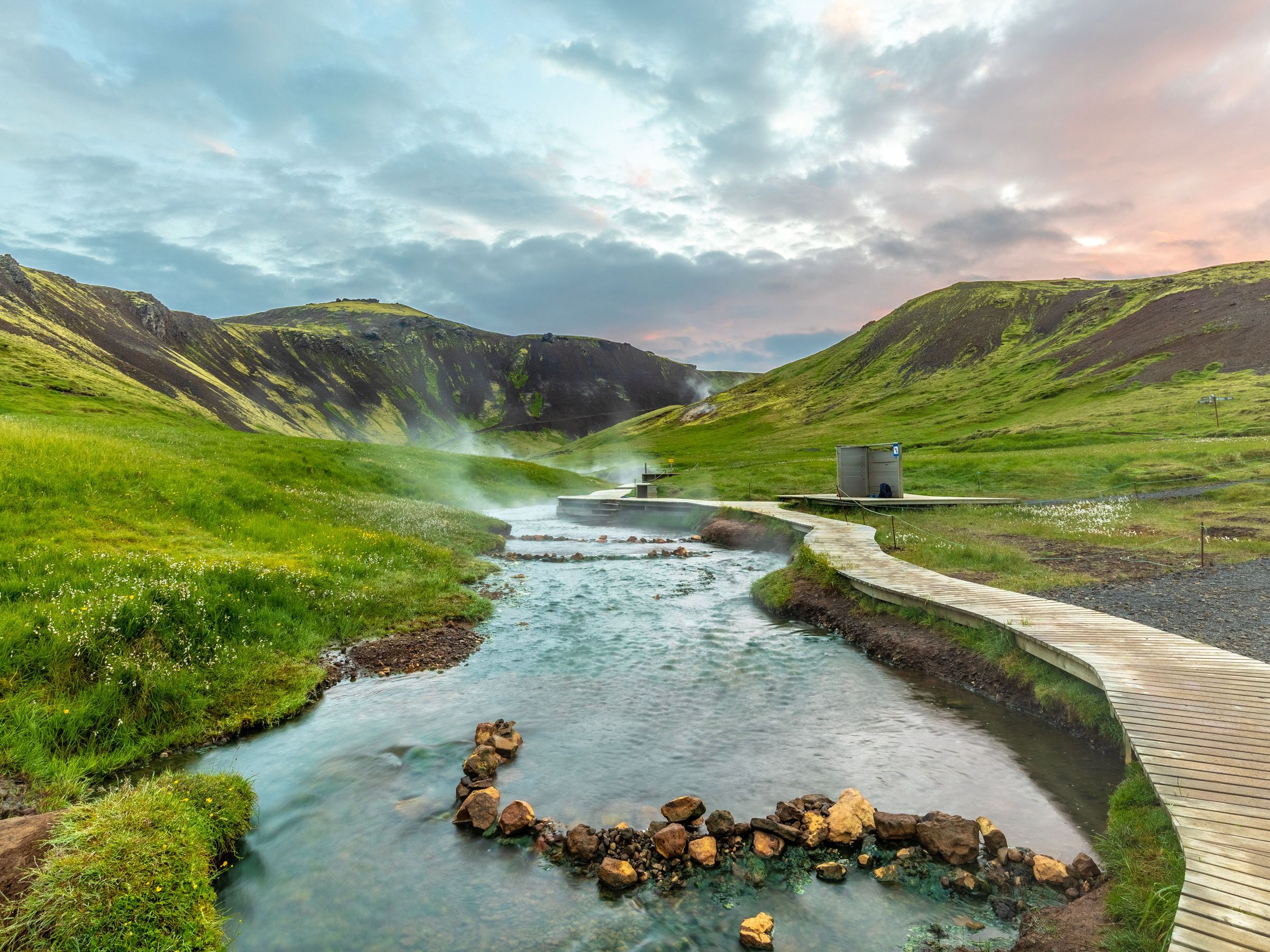 Geothermal river and hot springs of Reykjadalur between green mountains