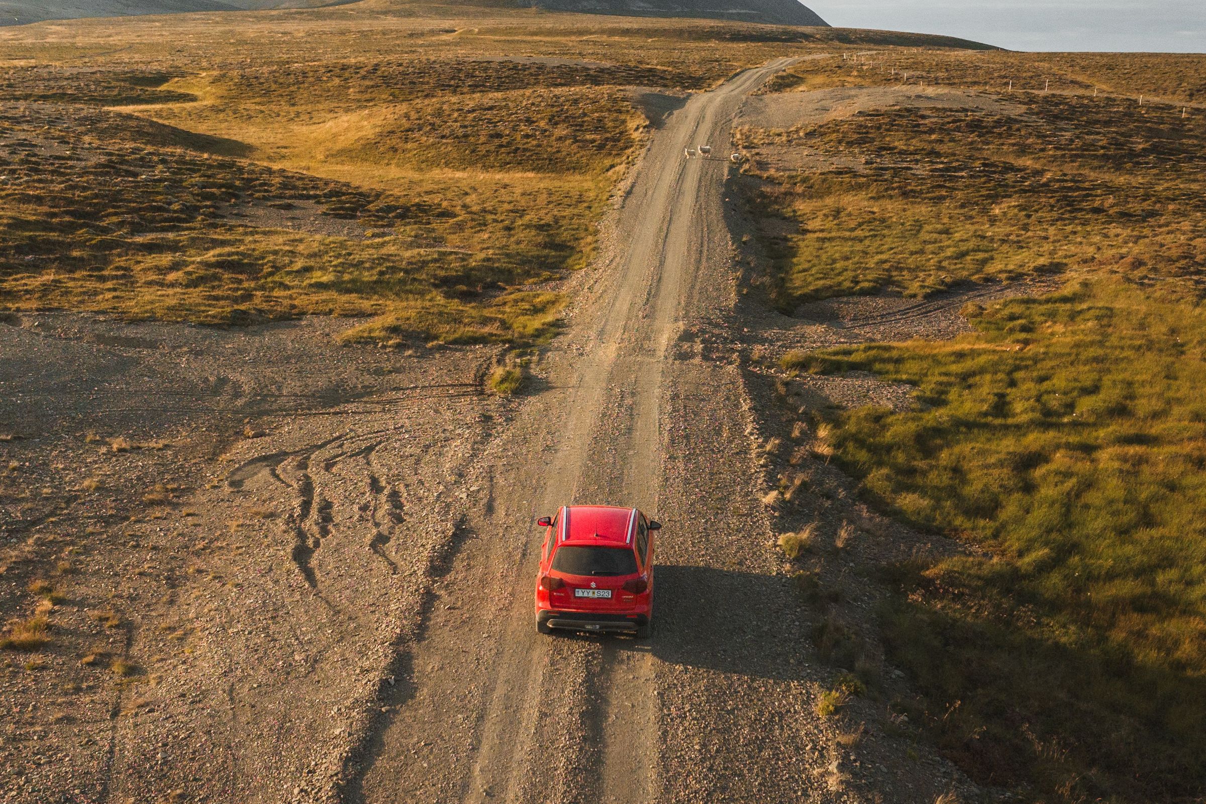 Coche rojo por una carretera de tierra en Islandia