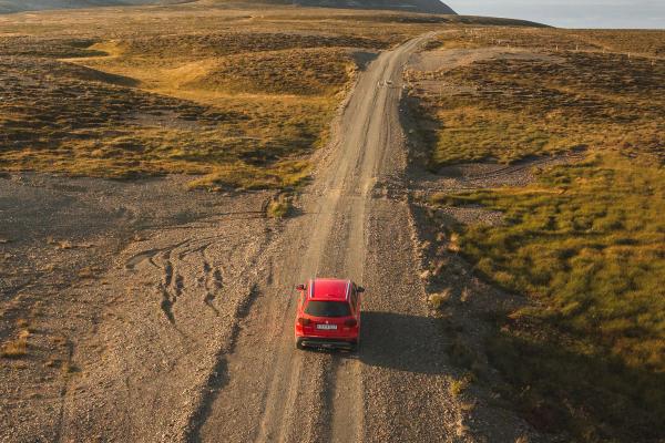 Coche rojo por una carretera de tierra en Islandia