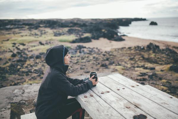 Girl sittin on a bench drinking coffee in Iceland