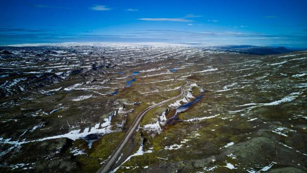 an aerial view of a road going through a snowy landscape in the highlands in iceland.