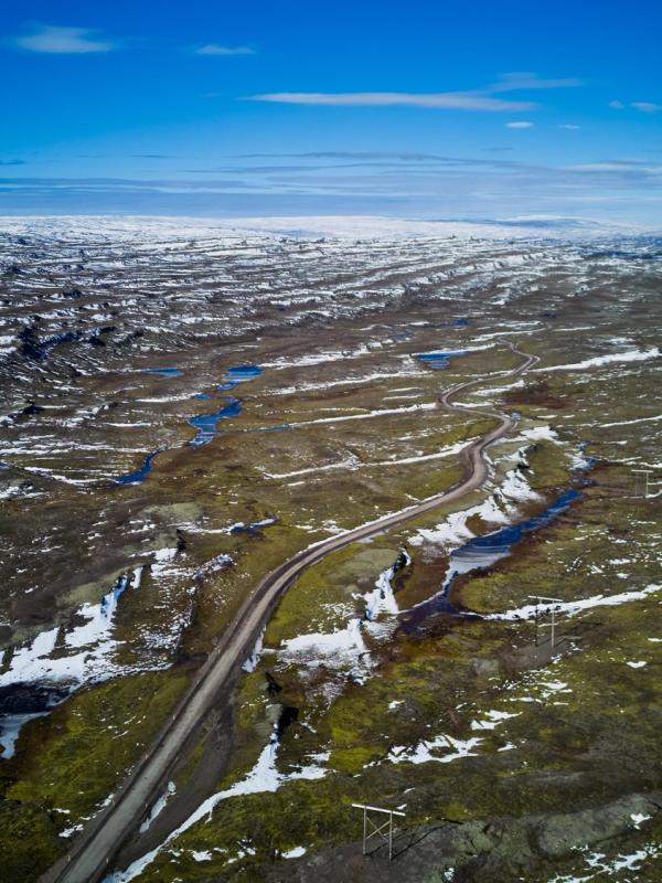 an aerial view of a road going through a snowy landscape in the highlands in iceland.