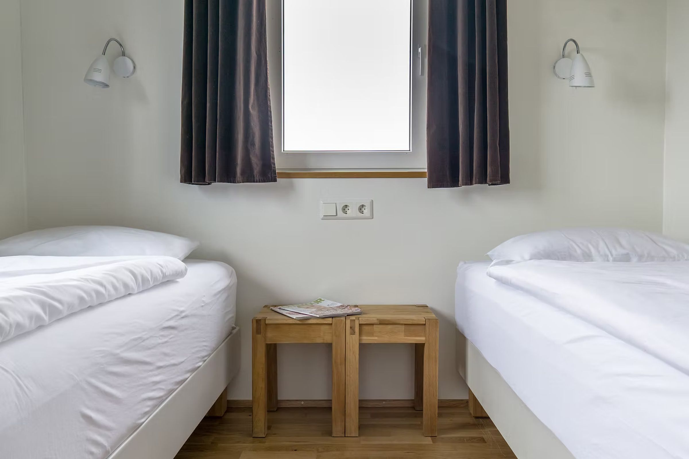 un dormitorio con dos camas, una mesita de noche y una ventana.