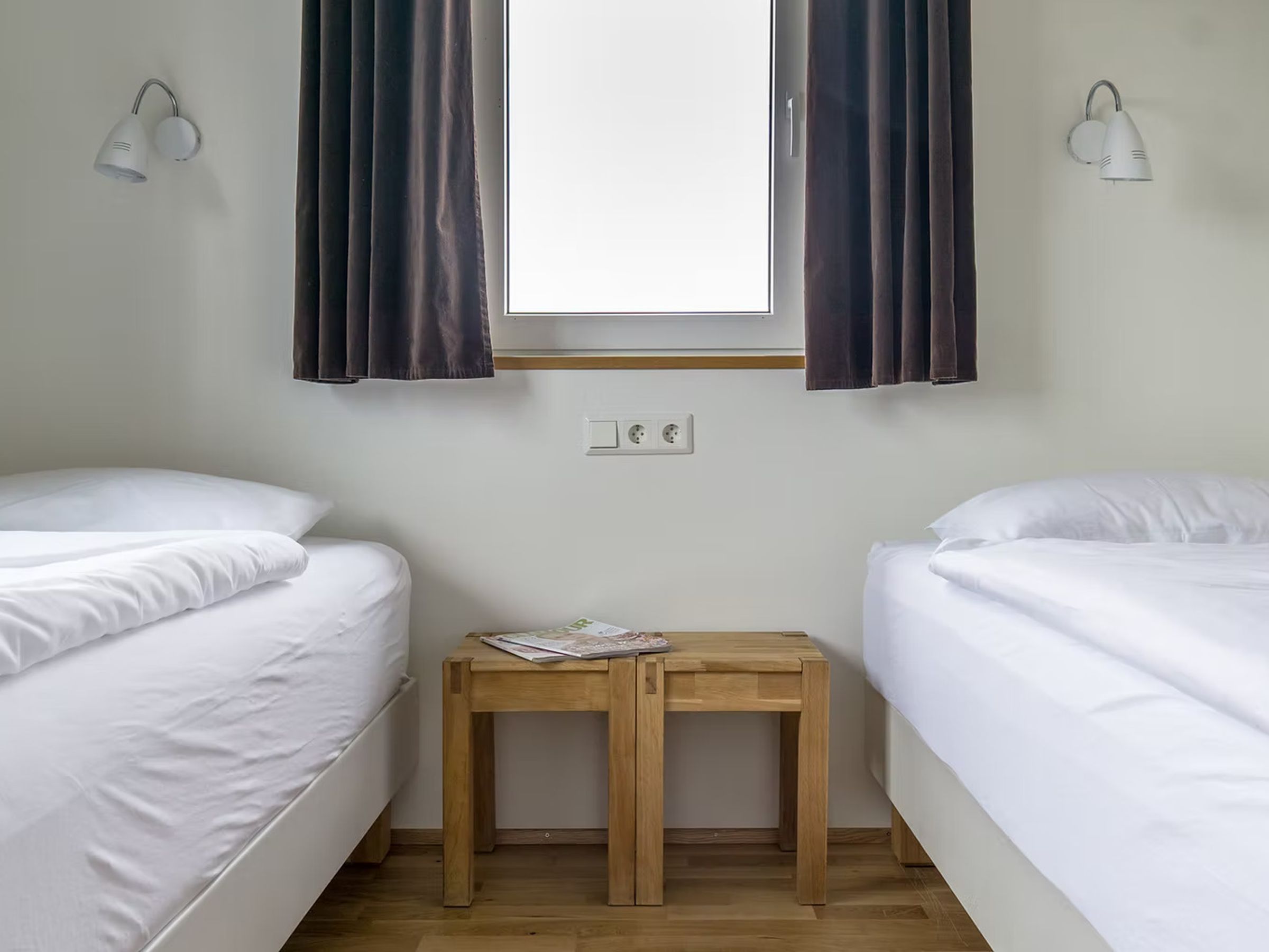 un dormitorio con dos camas, una mesita de noche y una ventana.