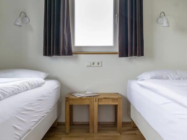 un dormitorio con dos camas, una mesita de noche y una ventana.