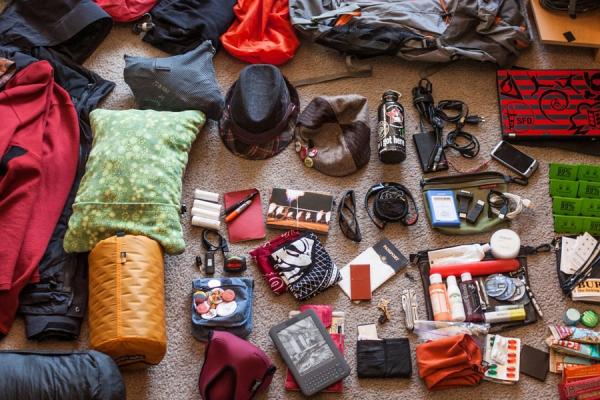 A wide array of clothing, electronics, and travel gear spread out on a carpet.