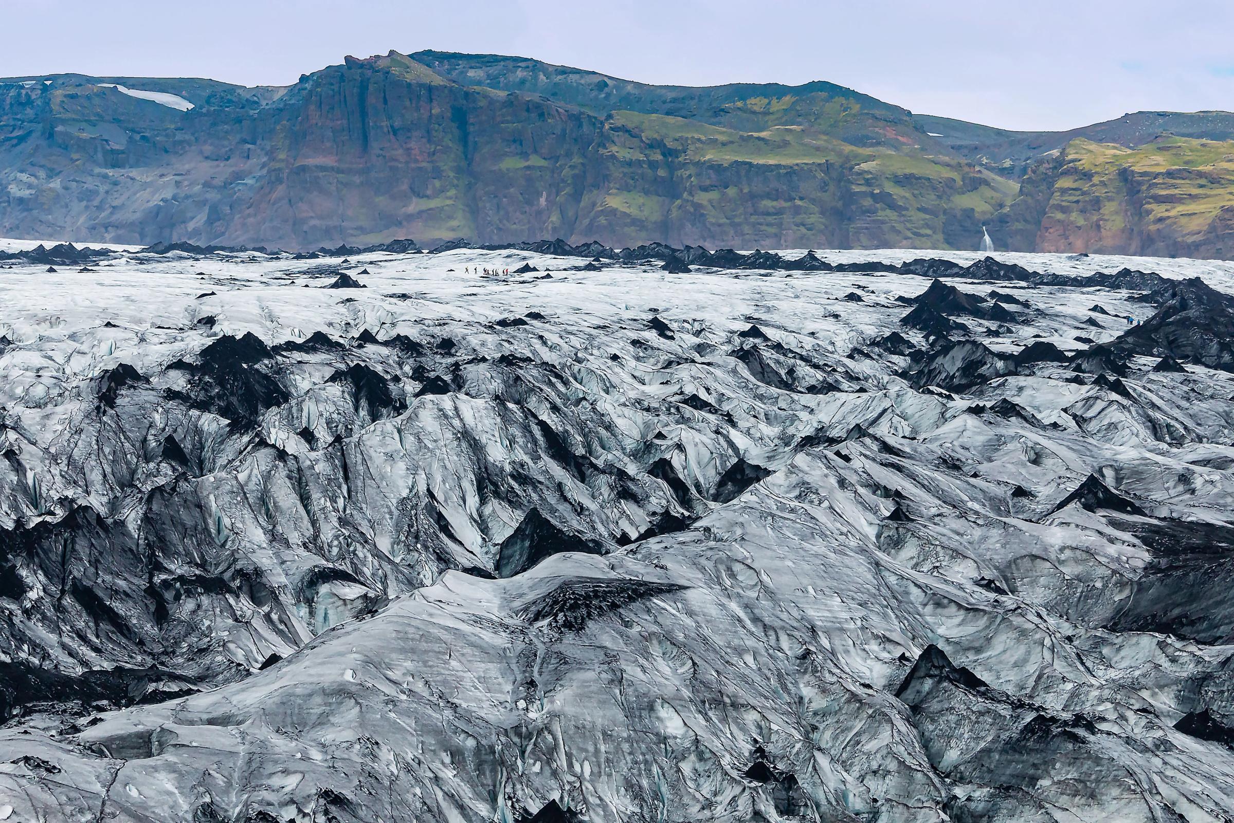 a glacier with a moss covered mountain in the background