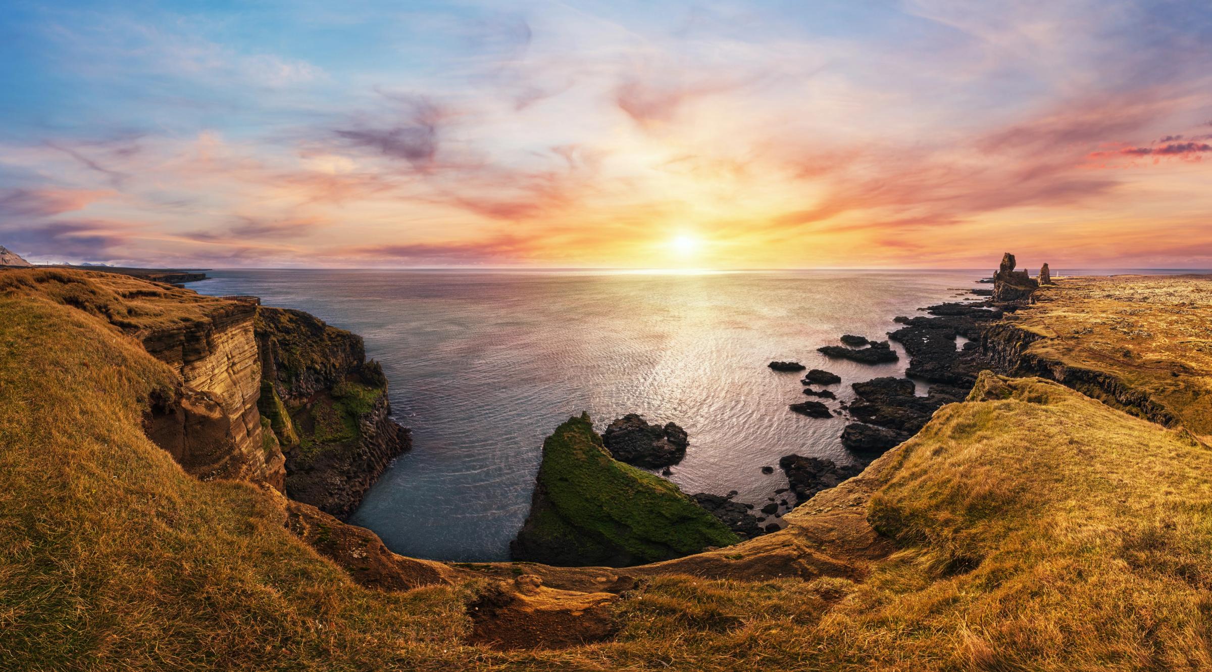 Rugged coastline at sunset with cliffs and sea stacks.