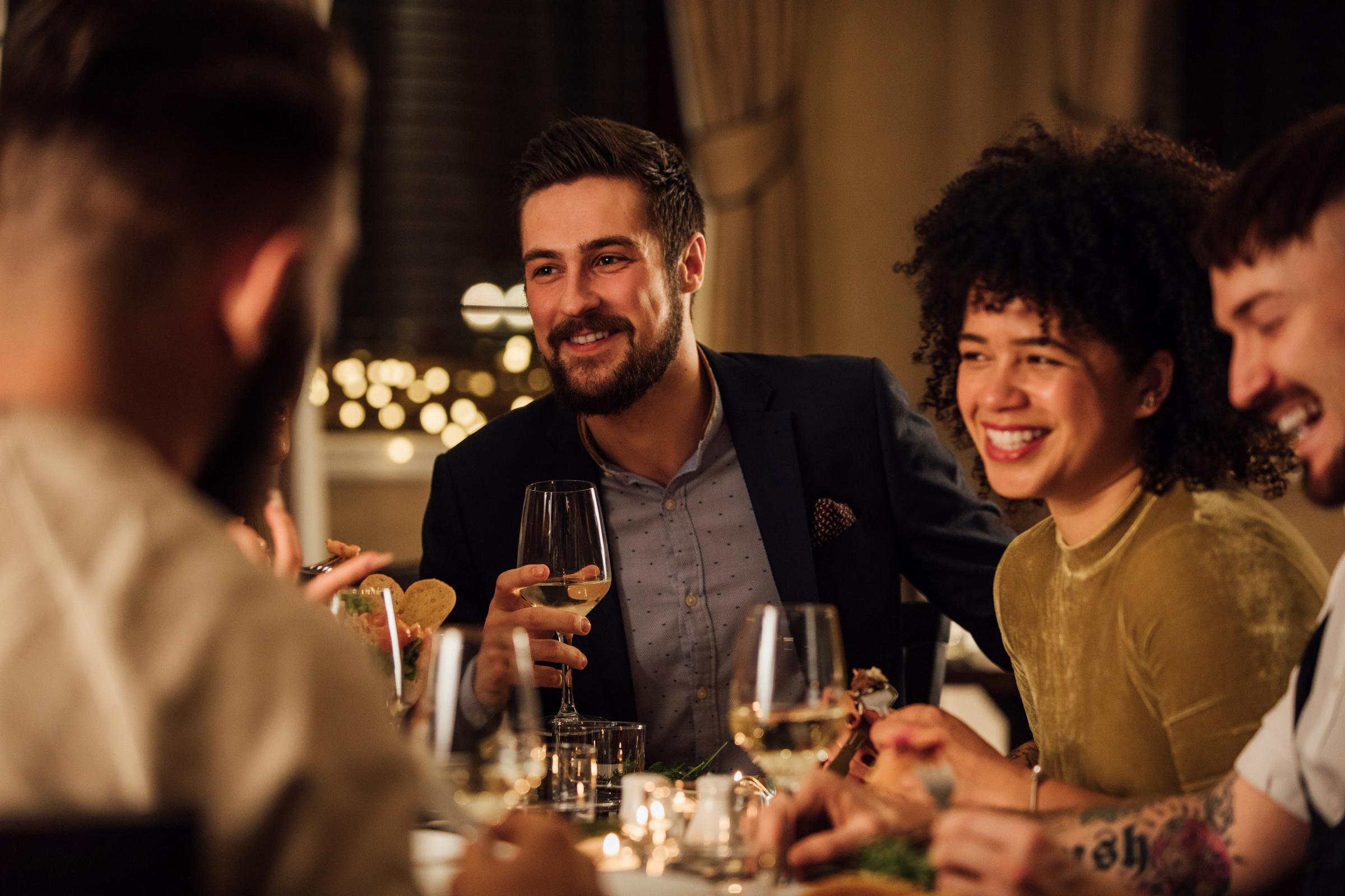 A diverse group of friends smiling and conversing at a dinner party.